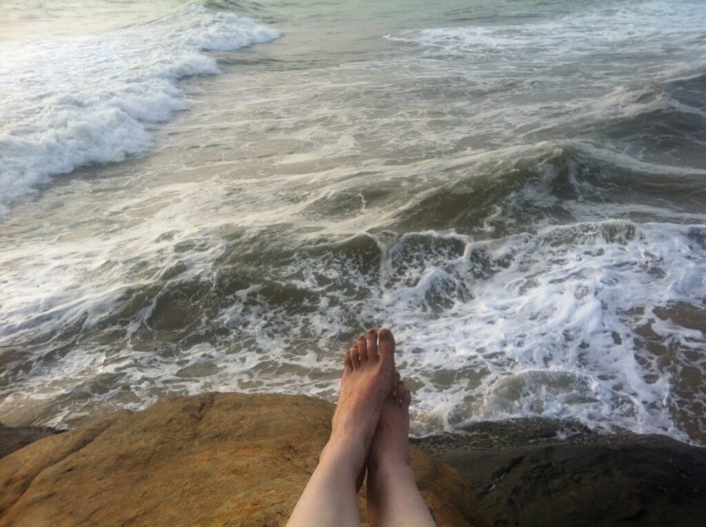 Füße auf einem Cliff Richtung Meer zeigend